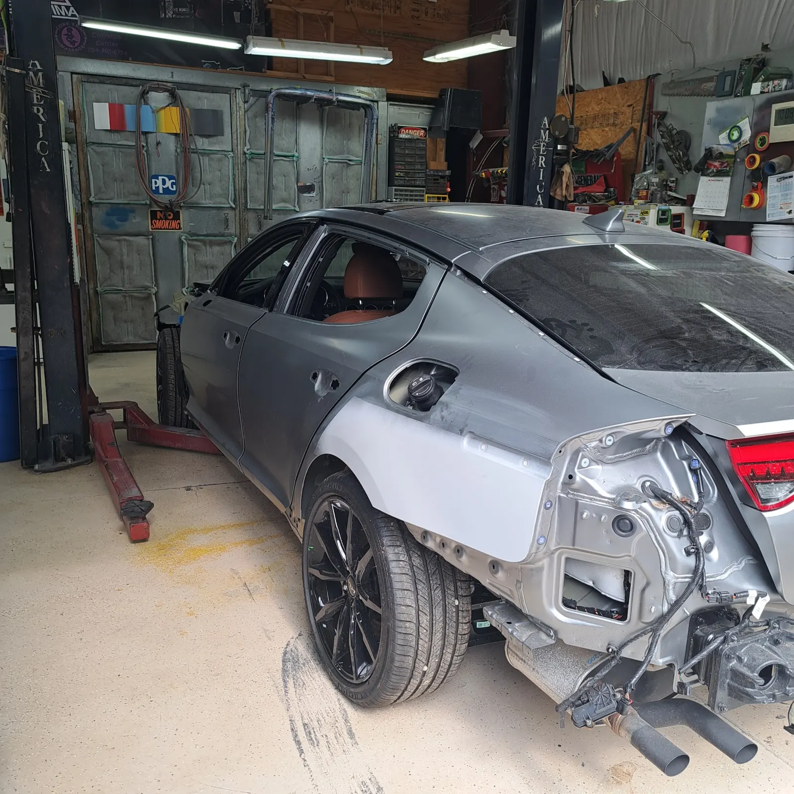 Disassembled car body undergoing quarter panel repair on lift — The ARK Body Shop and Collision Center in Concord