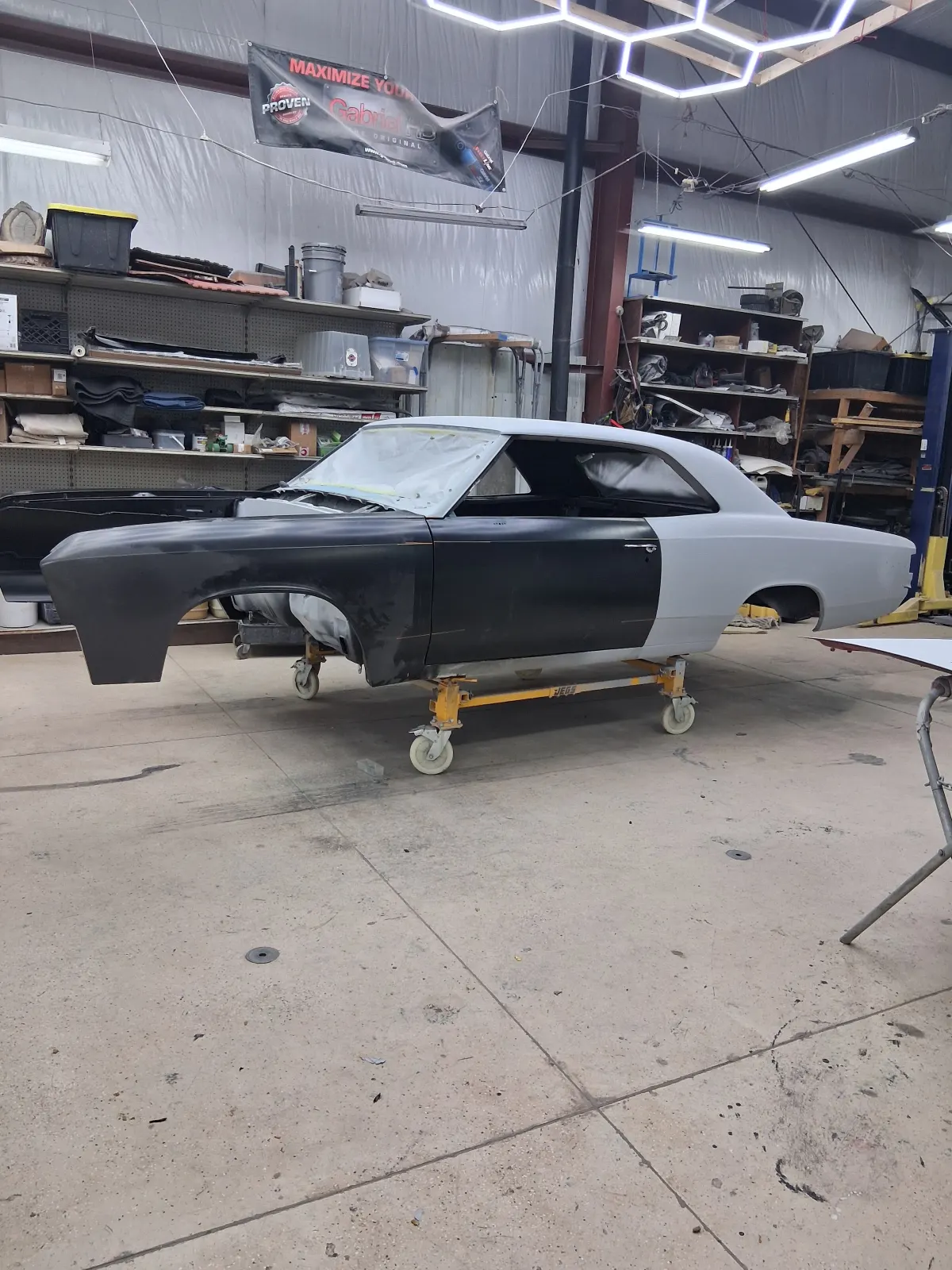 Vintage car shell mounted on dolly inside body shop — The ARK Body Shop and Collision Center in Concord